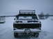 1979 Ford Bronco - A black 1979 Ford Bronco is parked in a snowy landscape, viewed from the rear, equipped with a roof rack.