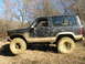 1996 Ford Bronco - This SUV is heavily coated in mud, suggesting it has been driven off-road. The tires are large and suitable for rough terrain.