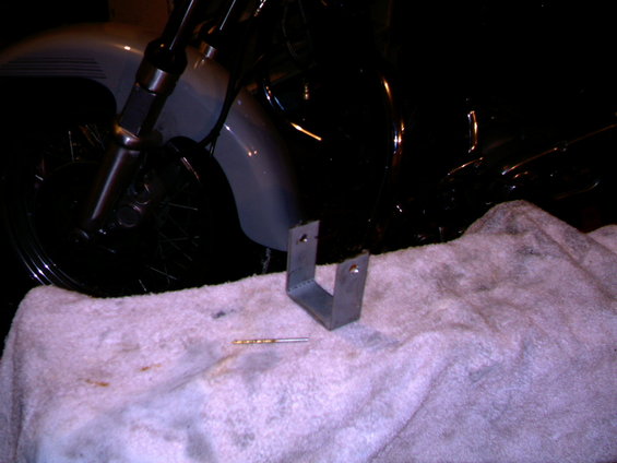 Motorcycle front wheel and fender with a metal bracket and drill bit on a towel