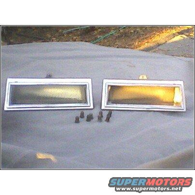 Two rectangular car side marker lights with chrome trim and screws on a gray tarp