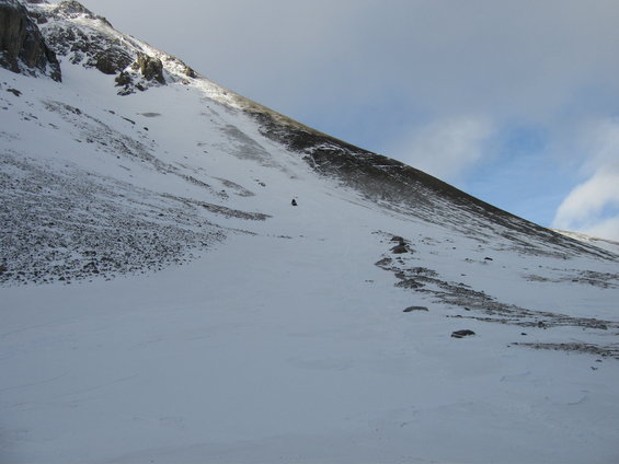 Snowmobile on a vast, snow-covered mountainside under a cloudy sky