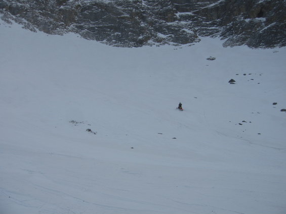 Snowmobile on a snowy slope with rocky mountains in the background