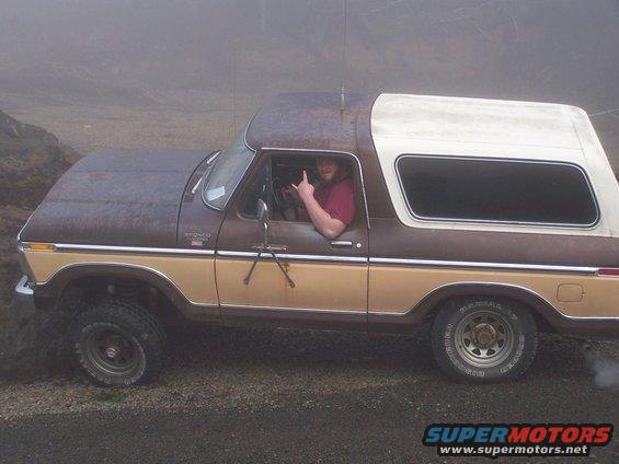 Driver in a 1978 Ford Bronco gives a rock-on hand signal while off-roading