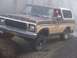 1978 Ford Bronco - A 1978 Ford Bronco drives off-road through fog, its front end angled towards the viewer.