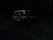 1978 Ford Bronco - This classic SUV is parked in a wooded area after dark, with its rear facing the camera.