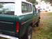 1979 Ford Bronco - The rear of a green 1978 Ford Bronco with a white camper shell is visible, parked in a grassy area.