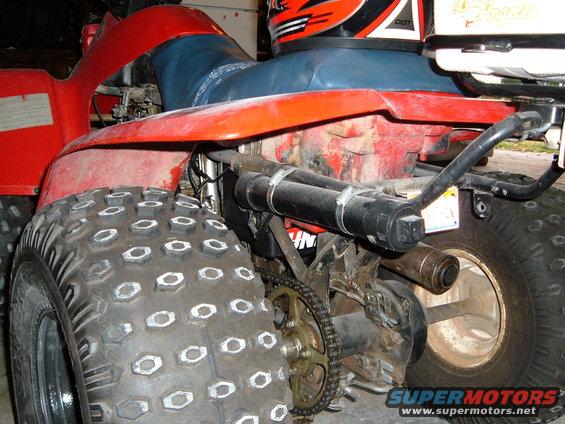 Red all-terrain vehicle rear view, showing knobby tires, exhaust, and chain drive