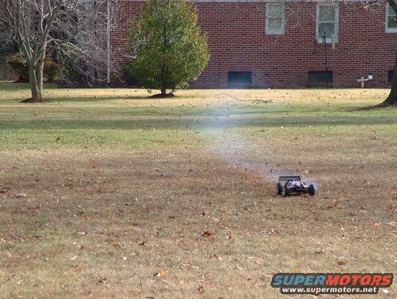 Remote control car on dry grass, kicking up dust