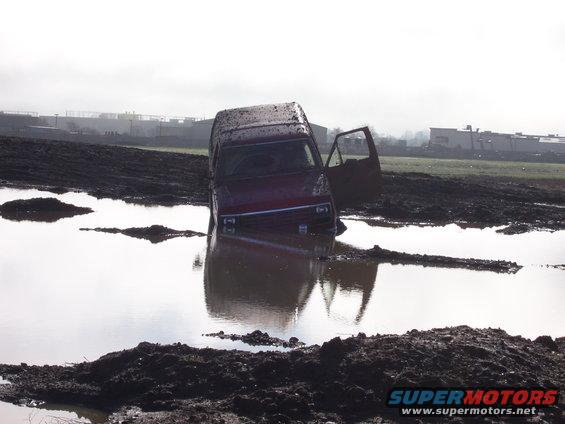 van stuck in muddy water, driver's door open