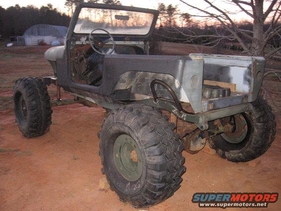 Olive drab Jeep CJ-series body with large off-road tires, missing doors and hood