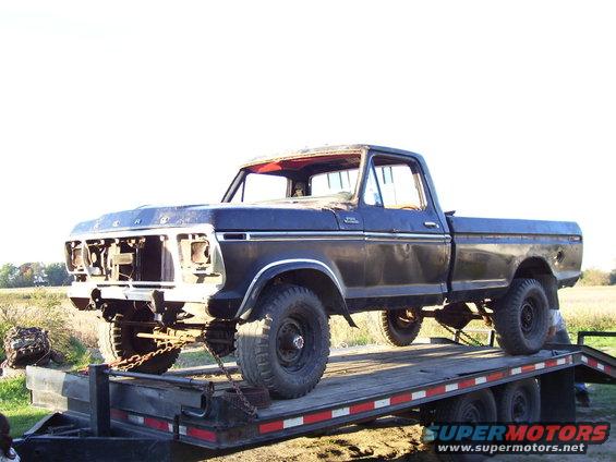 Dark blue 1979 Ford pickup truck on a flatbed trailer, front grille missing, some rust visible