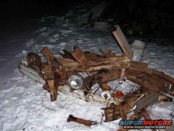 Rusted vehicle frame with two round headlights in snow