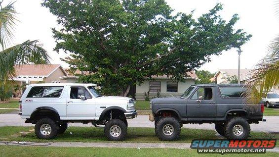 Two lifted Ford Broncos parked side-by-side on a residential street