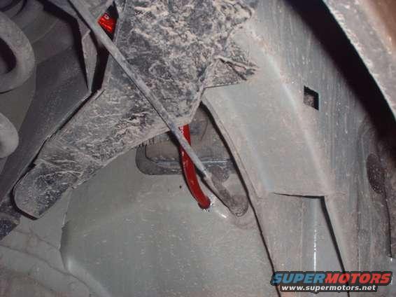 Close-up of vehicle undercarriage showing suspension components and a red hose