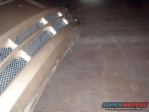 Tan car grille with three horizontal bars and mesh backing, viewed from the front-right