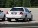 2003 Ford Crown Victoria - A white 2003 Ford Crown Victoria is parked next to another vehicle, showing its rear end and tinted windows.