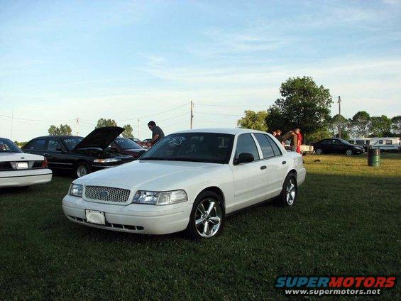 White 2003 Ford Crown Victoria with chrome wheels parked on grass
