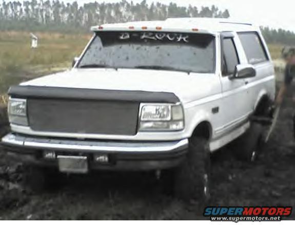 White 1995 Ford Bronco with "D-ROCK" on windshield, stuck in mud
