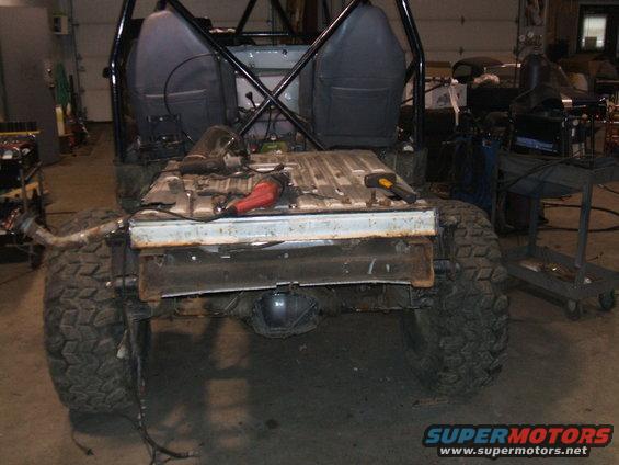 Rear view of disassembled SUV with large tires and roll cage