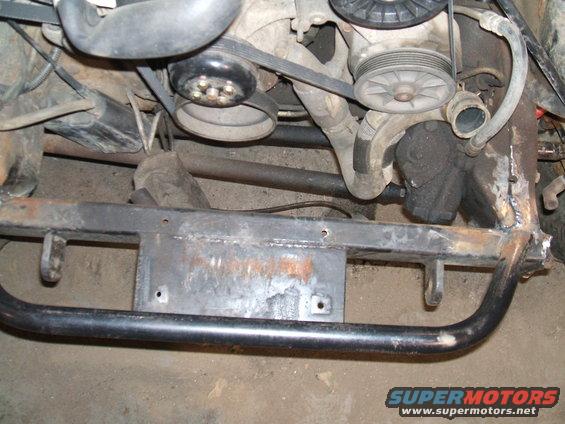 Close-up of engine pulleys, belts, and frame structure with visible welds