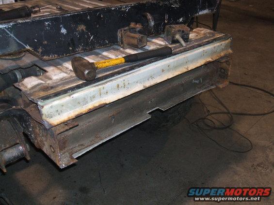 rusted frame section with a sledgehammer and some metal brackets on top