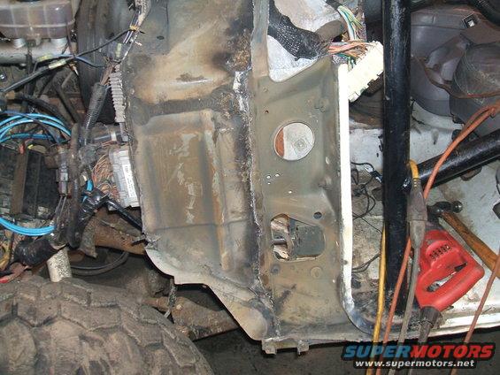 Close-up of vehicle frame damage and repair work, showing wiring and metal structure