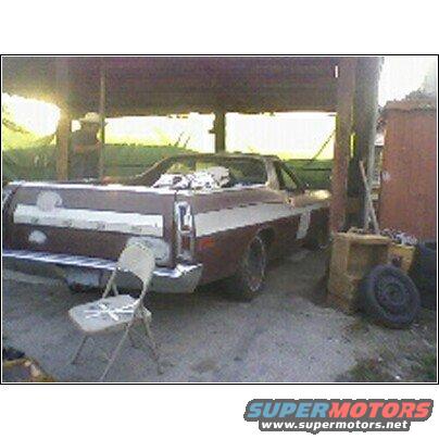 1972 Ford Ranchero, brown with white stripe, parked under a wooden shelter. Rear view