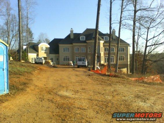 Construction site with a large house, two trucks, and a portable toilet