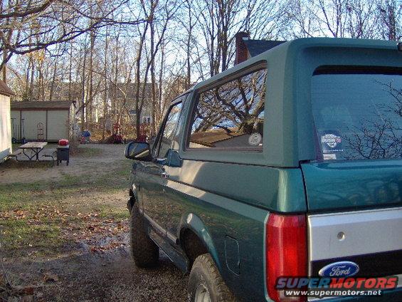 Green Ford Bronco, rear quarter view, parked in a yard with bare trees