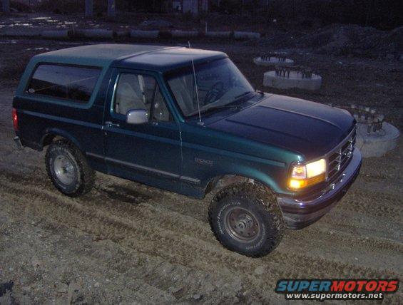 Green Ford Bronco parked on dirt lot