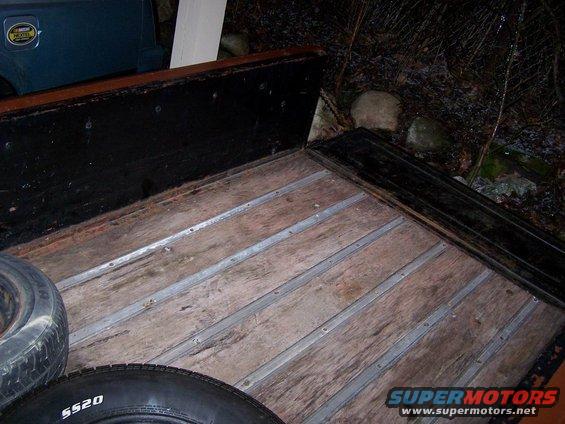 Truck bed with wooden planks and metal strips, two tires visible. One tire has "5520" written on it