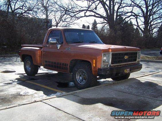 Orange pickup truck parked in a lot. It has a black grille and black trim on the side