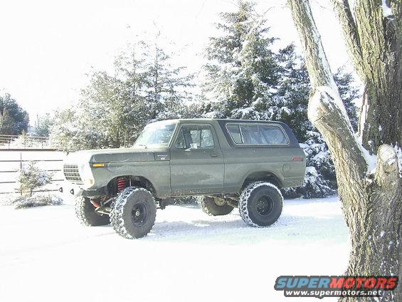 Lifted green 1978 Ford Bronco parked in a snowy landscape with trees