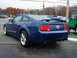 2007 Ford Mustang - A blue Ford Mustang coupe is parked on wet pavement, with other vehicles visible in the background.