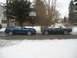 2007 Ford Mustang - Two Ford Mustangs, a modern coupe and a classic convertible, are parked side-by-side on a street with snow on the ground.