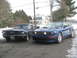 2007 Ford Mustang - Two Ford Mustangs, a classic convertible and a modern coupe, are parked side-by-side on a street with snow on the ground.