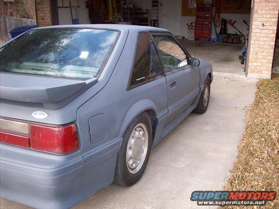 Gray Ford Mustang parked in a driveway next to a garage