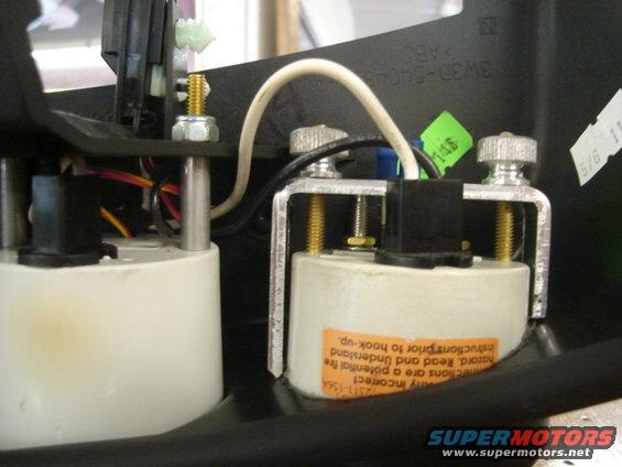 Dashboard gauges with wiring and a warning label