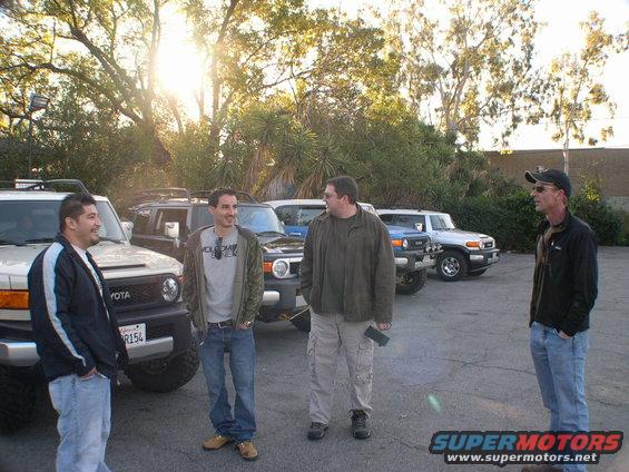 Four Toyota FJ Cruisers parked in a lot with four men standing nearby