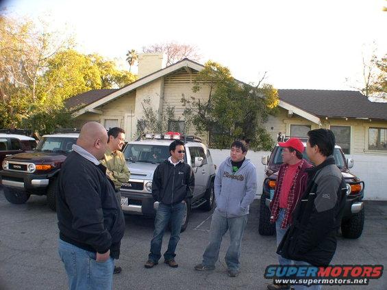 Group of men gathered around two Toyota FJ Cruisers, one silver and one dark red