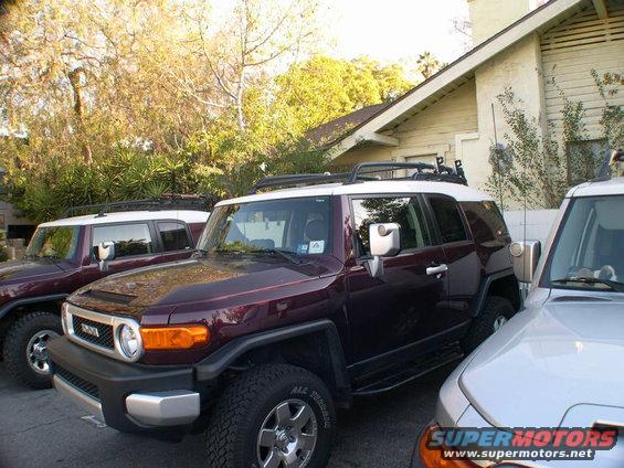 Maroon Toyota FJ Cruiser with white roof and roof rack, parked next to a silver vehicle