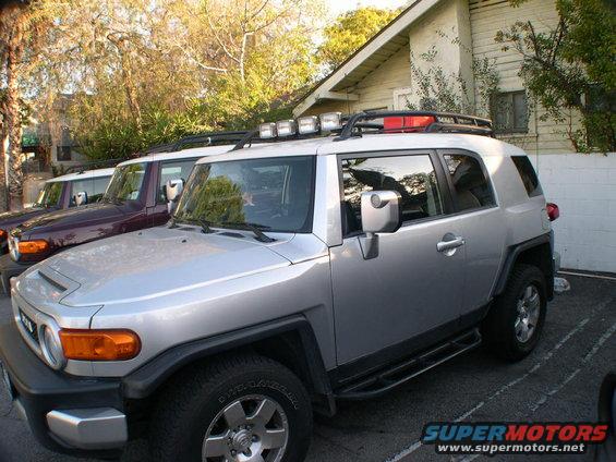 Silver 2007 Toyota FJ Cruiser with roof rack and lights parked next to other FJ Cruisers