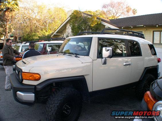 Tan Toyota FJ Cruiser parked in front of a house, with other FJ Cruisers behind it