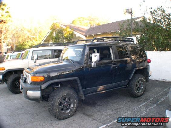 Black 2007 Toyota FJ Cruiser parked next to a white FJ Cruiser, viewed from the front three-quarter angle