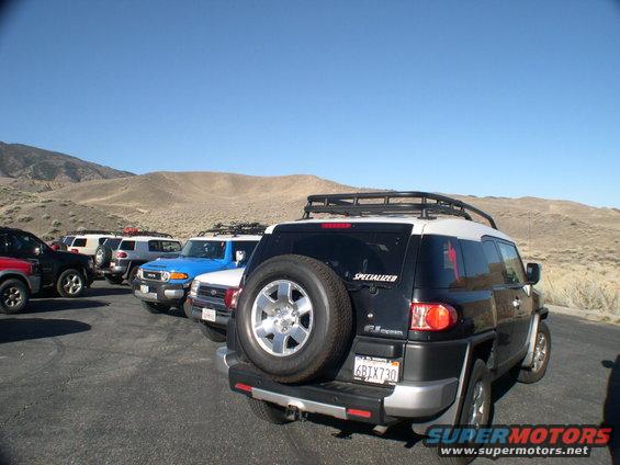 Several Toyota FJ Cruisers parked in a desert lot. One has a spare tire on the back