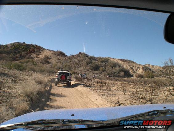 2007 Toyota FJ Cruiser leading a convoy on a dusty trail in a dry, hilly landscape