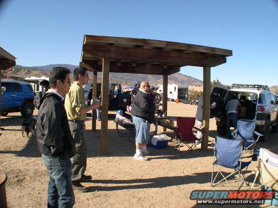 Blue FJ Cruiser parked, people gathered under a shelter, white FJ Cruiser with open hatch