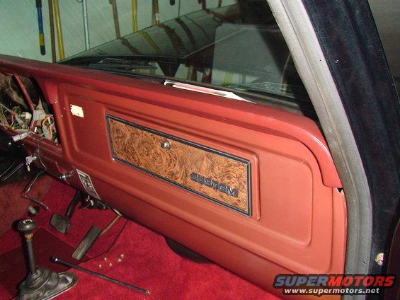 1979 Ford F-150 interior door panel with woodgrain trim and 'CUSTOM' badge, showing exposed wiring and pedals