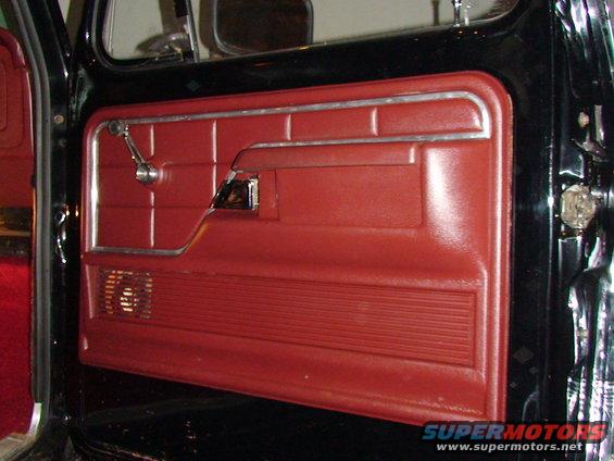 Close-up of a red truck door panel with chrome window crank and door handle