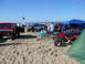 1988 Ford Bronco - A collection of vehicles and recreational equipment are gathered on a sandy beach under a clear blue sky.